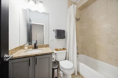 a bathroom with a granite countertop toilet sink and mirror