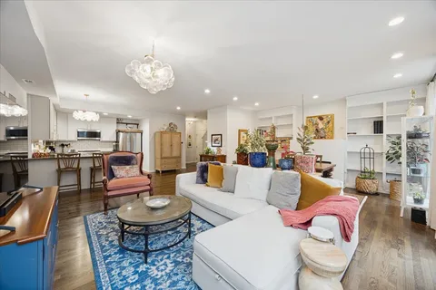 a living room with lots of furniture kitchen view and a table