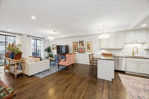 a living room with furniture two wooden floor and a kitchen