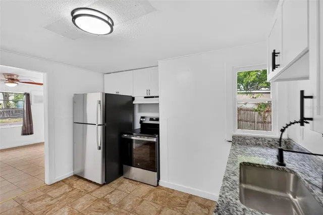 a kitchen with stainless steel appliances granite countertop a refrigerator a sink a stove and a refrigerator