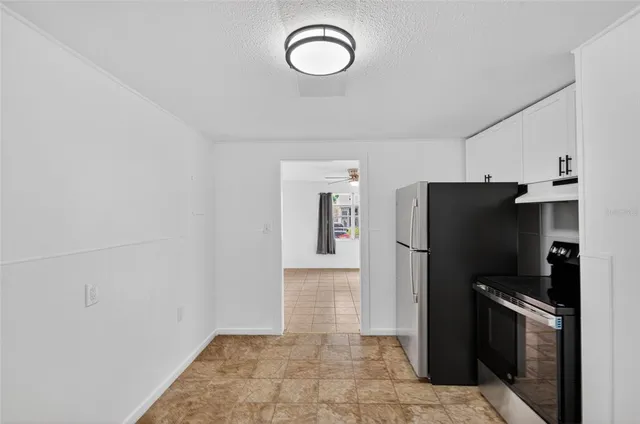 a view of a refrigerator in kitchen and an empty room