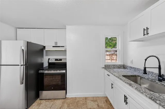 a kitchen with stainless steel appliances granite countertop a refrigerator sink and stove