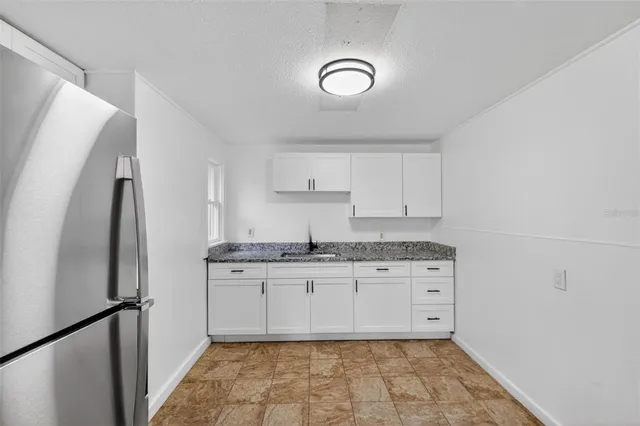 a kitchen with granite countertop a sink stove and refrigerator