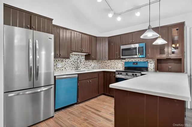 a kitchen with stainless steel appliances a refrigerator a sink a stove a microwave a center island and chairs