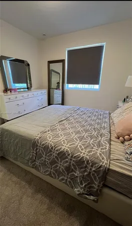 a bedroom with a bed and a flat tv screen on dresser
