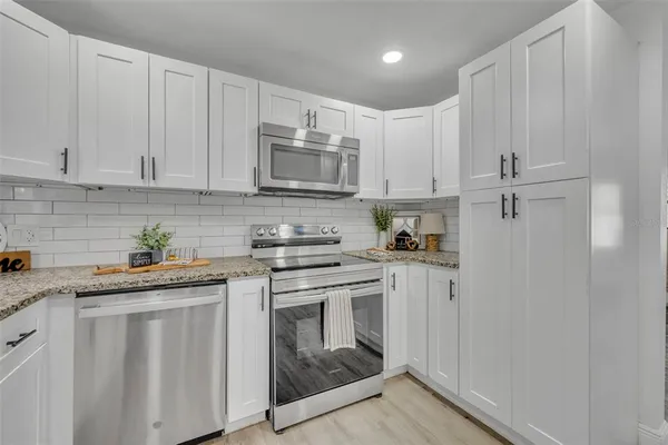 a kitchen with granite countertop white cabinets and white appliances
