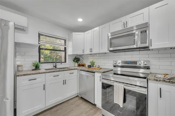 a kitchen with granite countertop white cabinets and appliances
