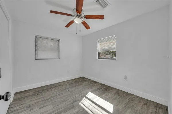 a view of empty room with wooden floor and fan