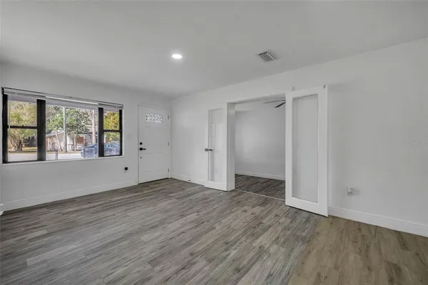 a view of an empty room with wooden floor and a window