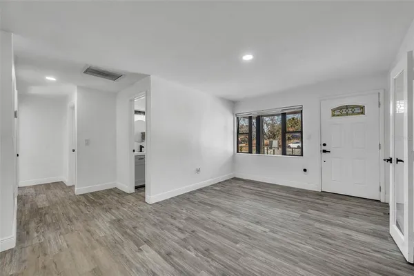 a view of an empty room with wooden floor and windows