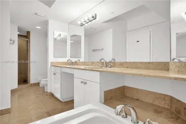 a spacious bathroom with a toilet a sink and a mirror