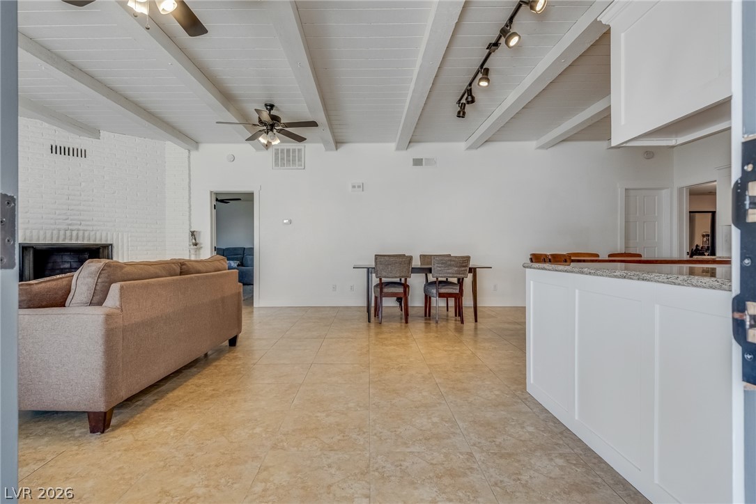 524 Swallow Cove Boulder City, NV 89005 - Photo 6 of 58 A spacious living area features exposed beam ceilings, a cozy fireplace, and durable tile flooring.