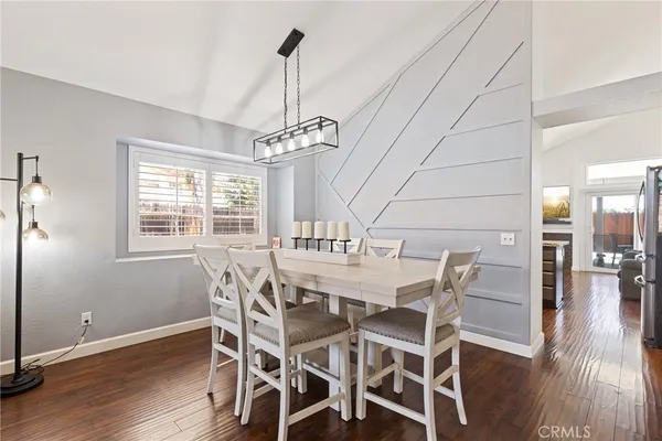 a dining room with wooden floor a chandelier a wooden table and chairs