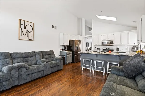 a living room with furniture kitchen and a wooden floor