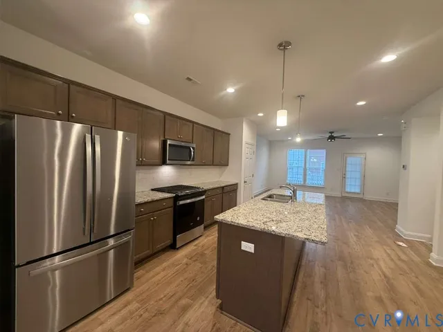 a kitchen with stainless steel appliances granite countertop a refrigerator a sink and a stove