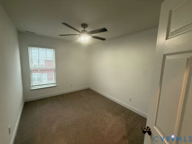 an empty room with a window and a fan