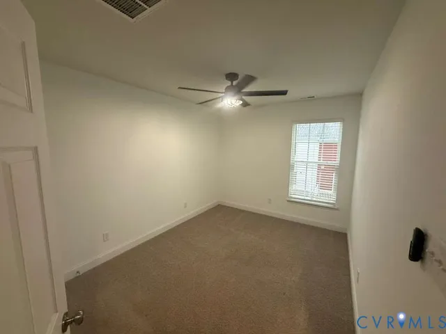 an empty room with a window and a ceiling fan