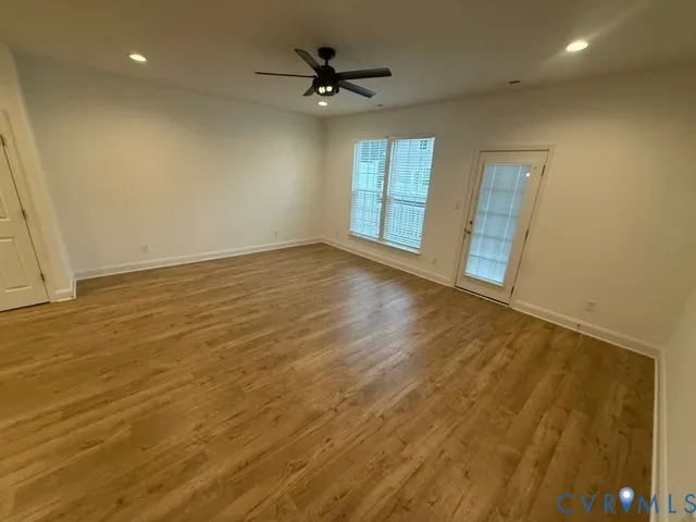 an empty room with windows and a ceiling fan