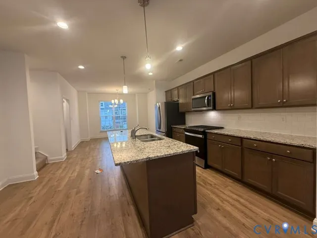 a kitchen with stainless steel appliances granite countertop wooden cabinets a stove top oven a sink and dishwasher