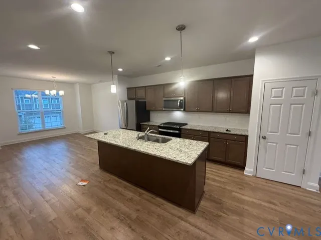 a large room with kitchen island a sink wooden floor and living room view