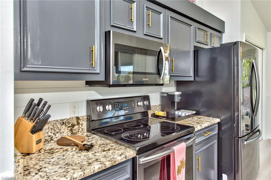21340 Lancaster Run, Unit 1327 Estero, FL 33928 - Photo 6 of 27 a kitchen with stainless steel appliances granite countertop a stove and a microwave