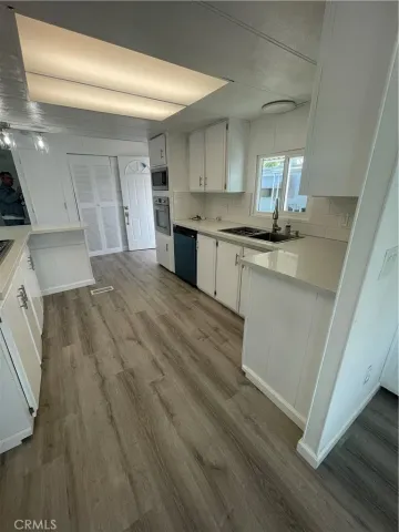 a kitchen with stainless steel appliances granite countertop a sink cabinets and wooden floor