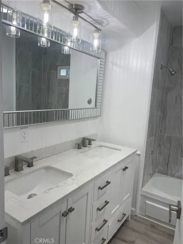 a bathroom with a sink vanity granite tub shower and a mirror