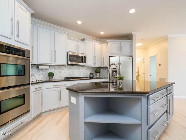 a kitchen with kitchen island granite countertop a sink and white cabinets