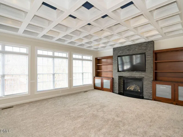 an empty room with windows fireplace and cabinet