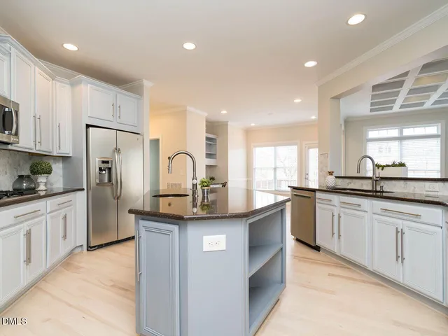 a kitchen with kitchen island granite countertop white cabinets and refrigerator