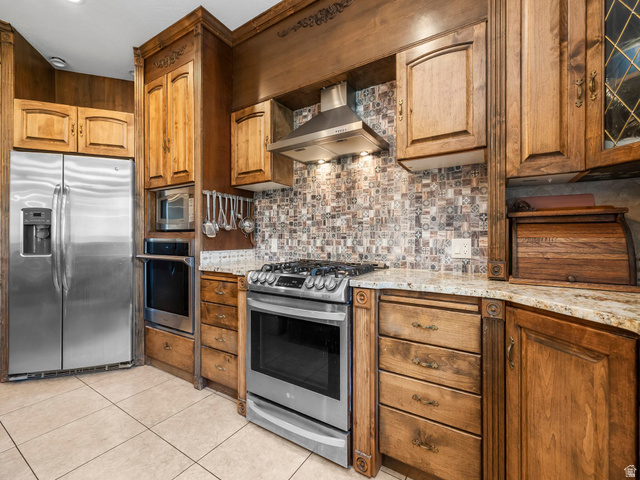 1317 South Pond Circle Mapleton, UT 84664 - Photo 9 of 63 Kitchen featuring custom wood cabinetry, stainless steel appliances, patterned tile backsplash, granite countertops, and light-toned floor tiling