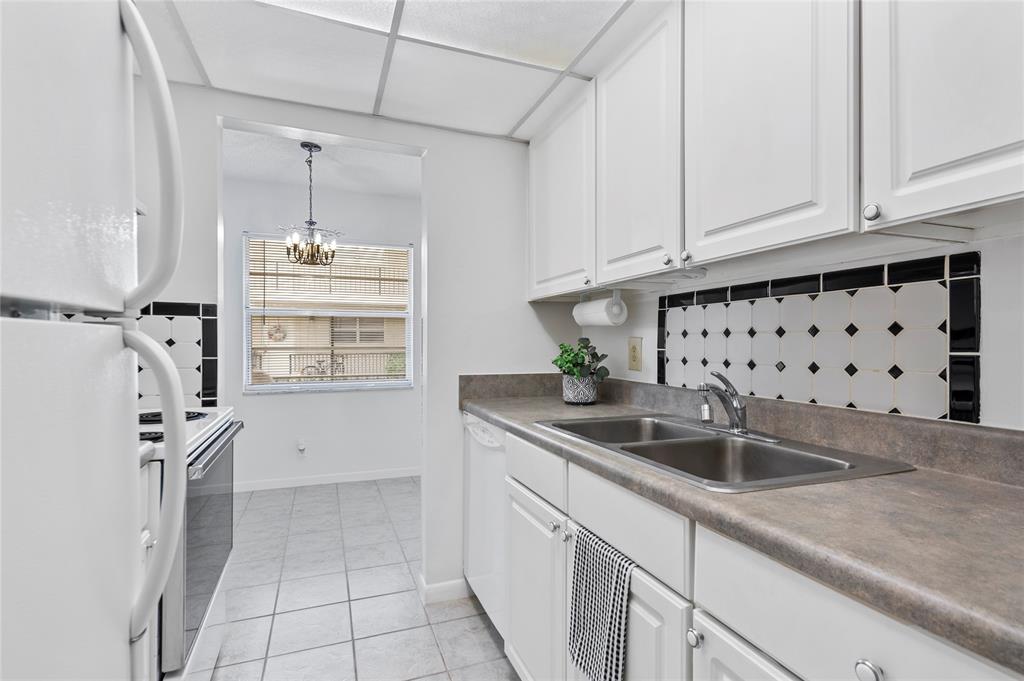 1230 Old Boynton Road, Unit 203 Boynton Beach, FL 33426 - Photo 6 of 25 a kitchen with granite countertop a sink and a refrigerator