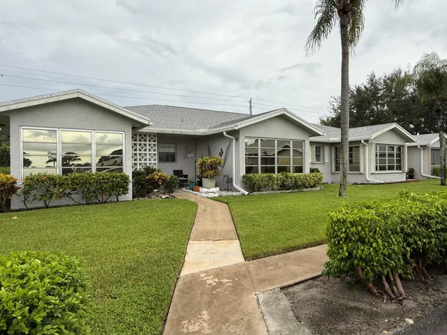 a front view of a house with a yard and potted plants