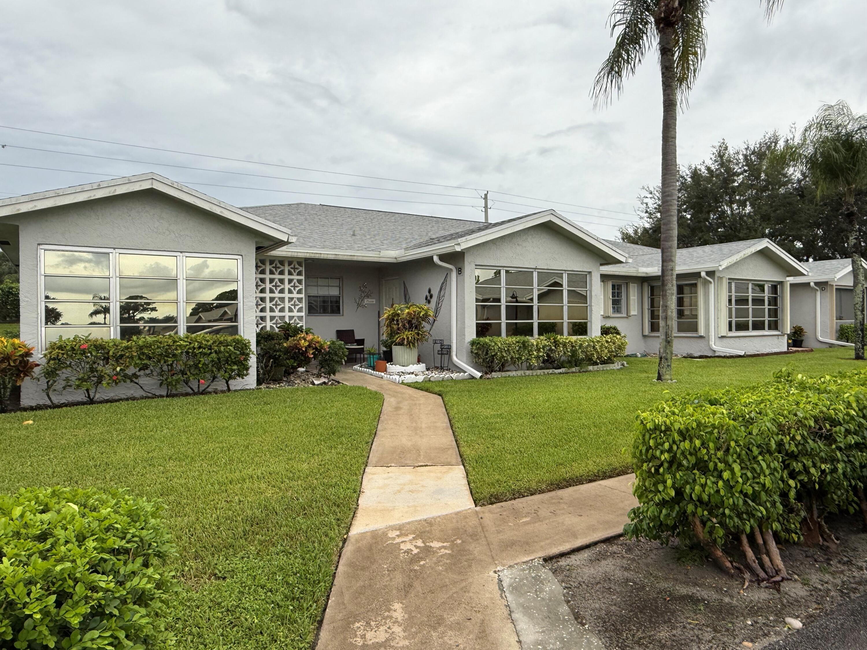 a front view of a house with a yard and potted plants
