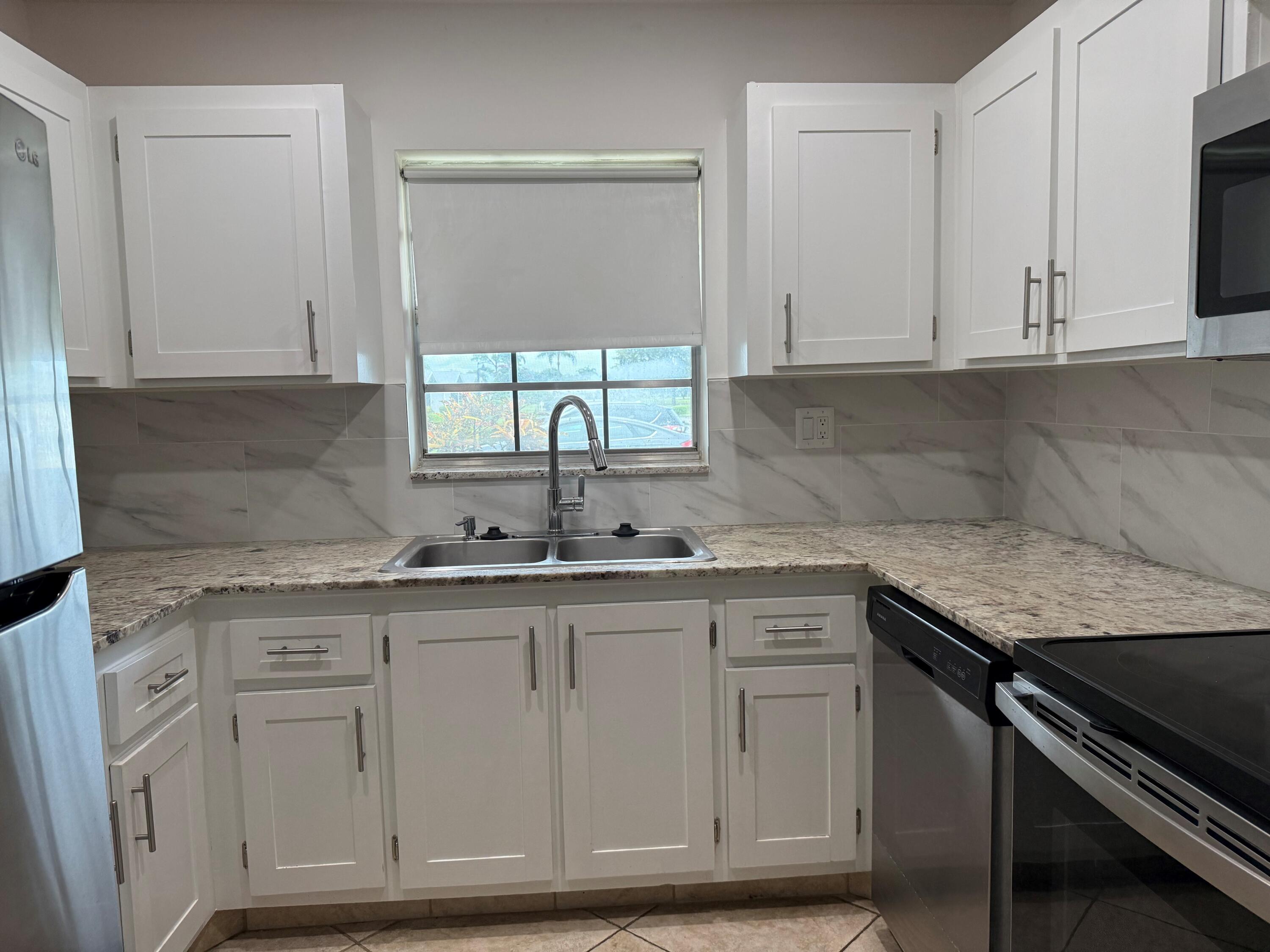 14676 Canalview Drive, Unit A Delray Beach, FL 33484 - Photo 10 of 33 a kitchen with granite countertop white cabinets and a sink