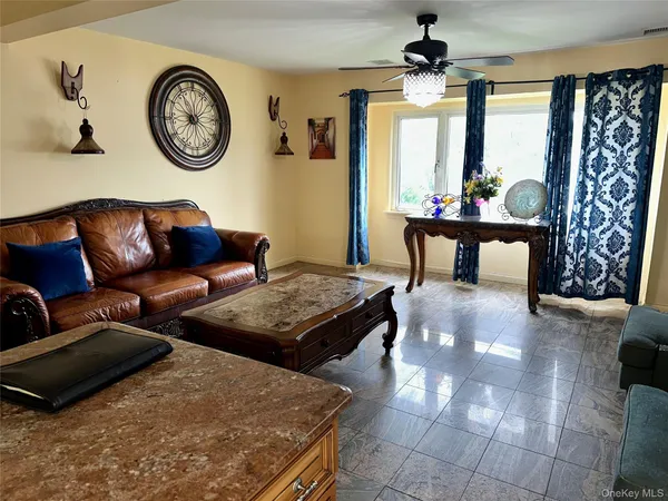 a living room with furniture a clock on wall and a window