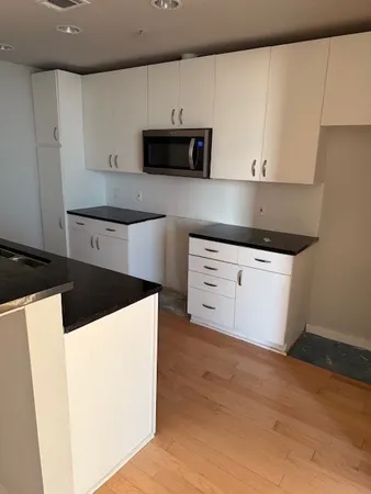 a kitchen with granite countertop white cabinets and stainless steel appliances