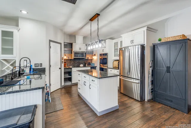 a kitchen with stainless steel appliances granite countertop a refrigerator a stove and a sink