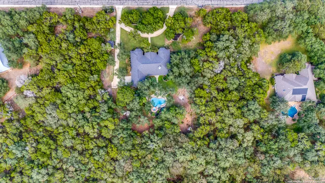 an aerial view of residential house with outdoor space and trees all around