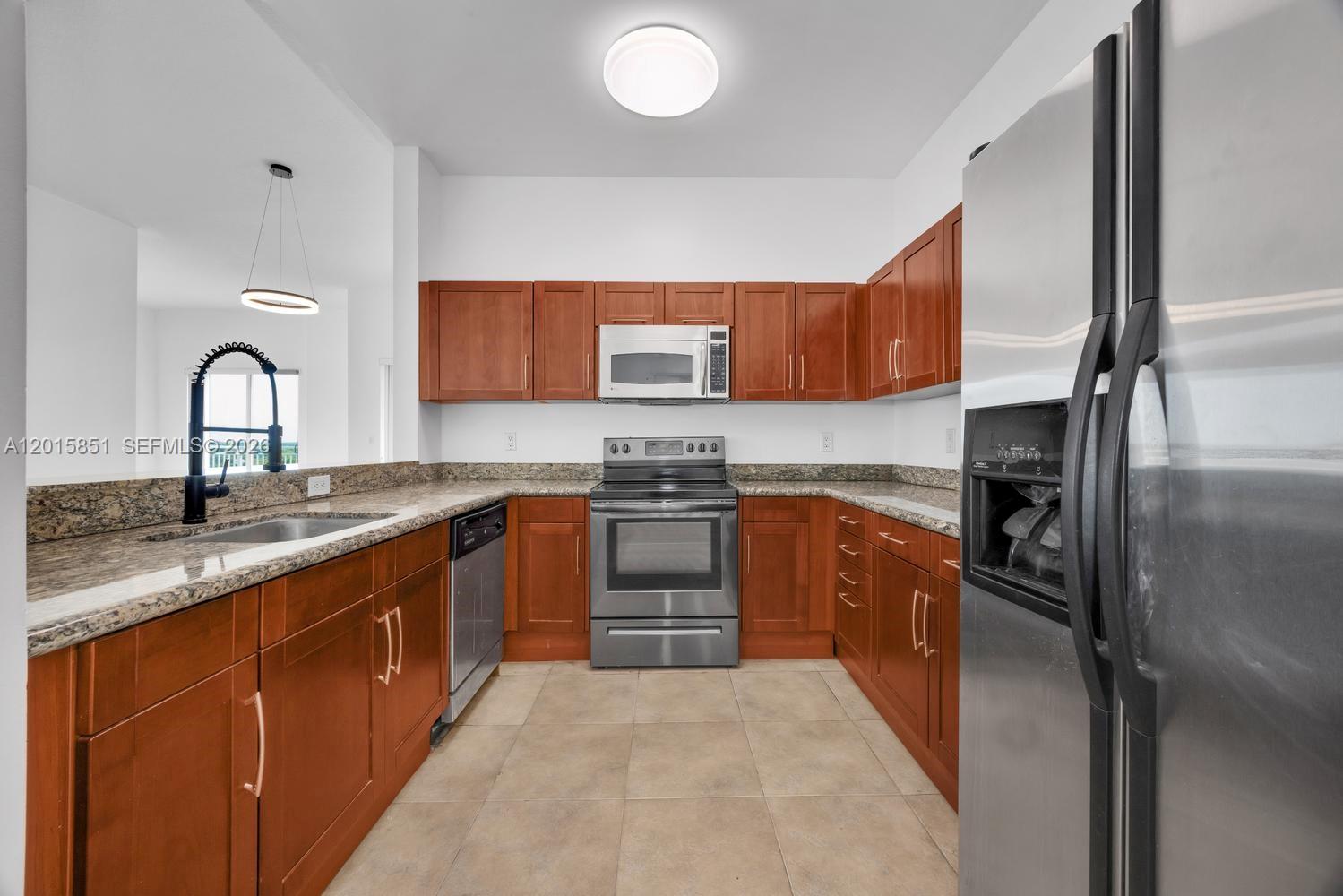 7275 Southwest 90th Street, Unit C719 Miami, FL 33156 - Photo 10 of 25 a kitchen with stainless steel appliances granite countertop a sink stove and refrigerator