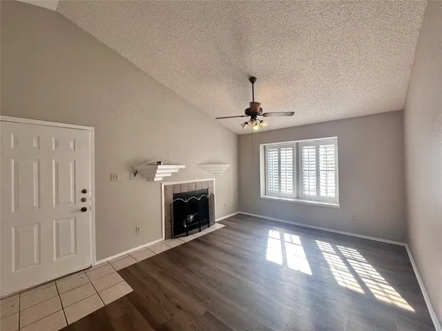 a view of an empty room with wooden floor fireplace and a window