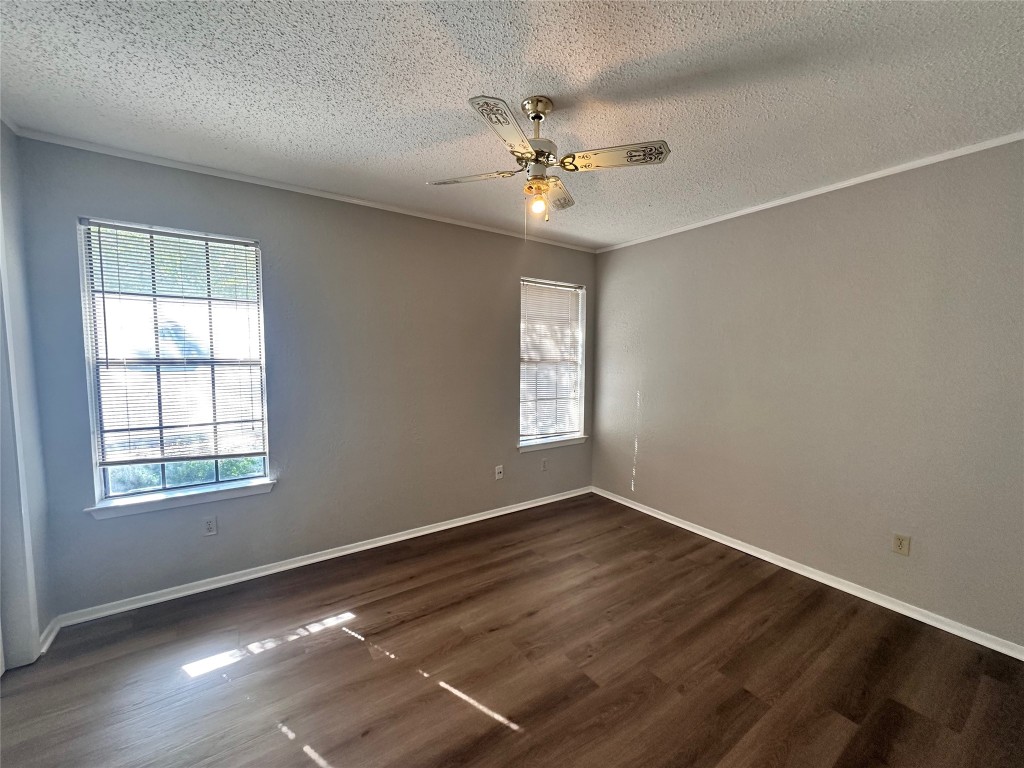 1411 Gracy Farms Lane, Unit 102 Austin, TX 78758 - Photo 8 of 12 an empty room with wooden floor fan and windows