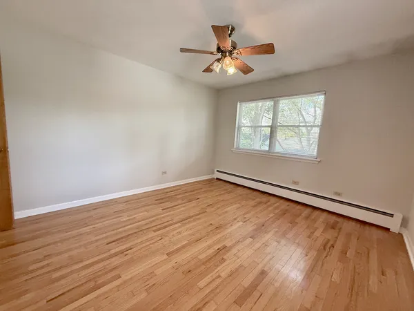 an empty room with wooden floor chandelier fan and windows
