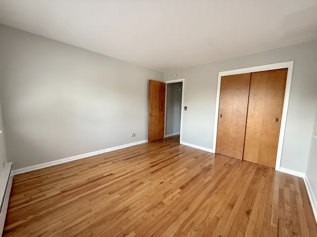 a view of an empty room with wooden floor and closet