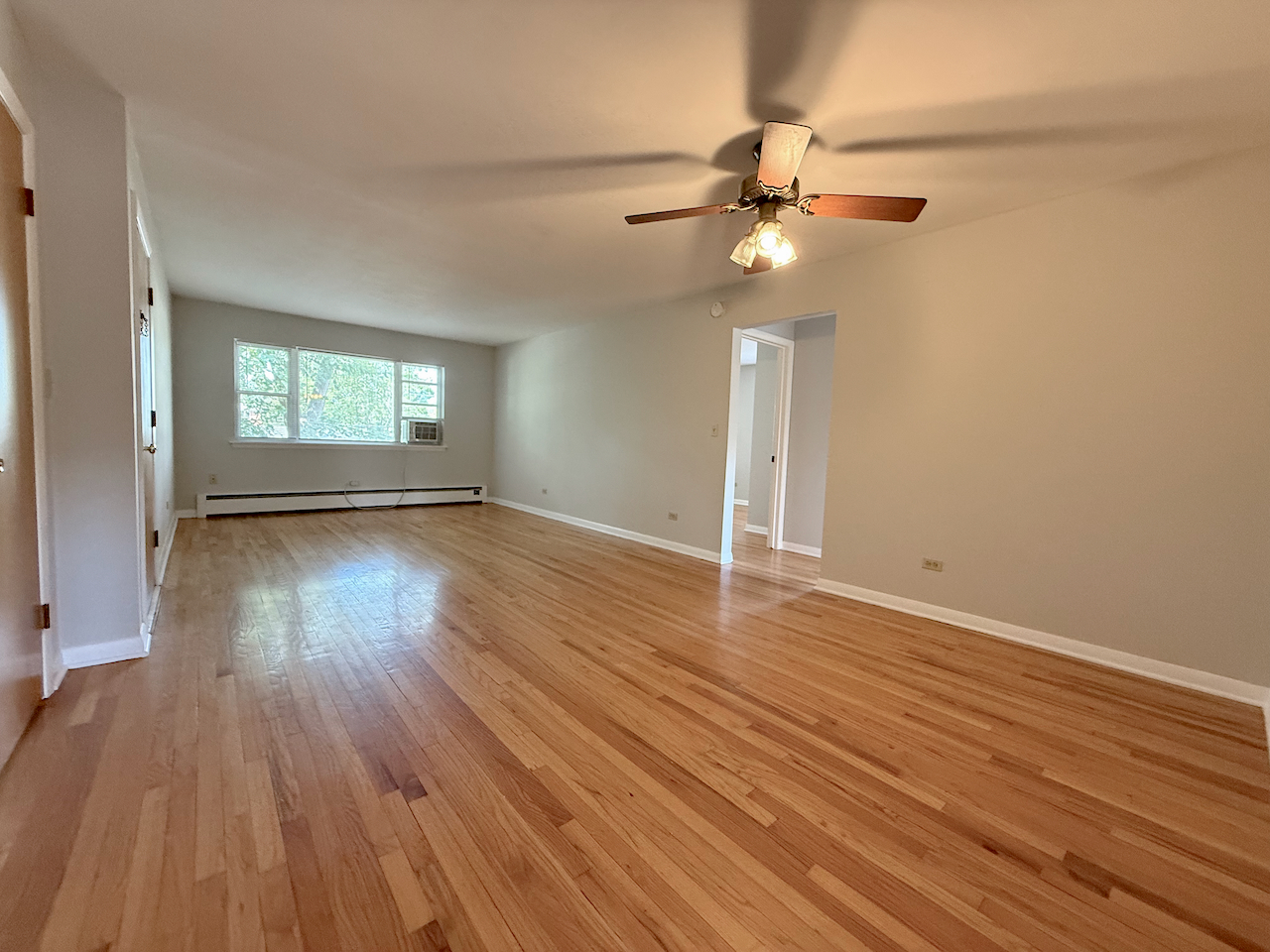 317 South Plum Grove Road, Unit 5 Palatine, IL 60067 - Photo 2 of 14 an empty room with wooden floor chandelier fan and windows