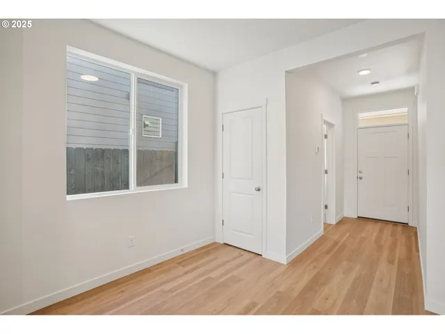 a view of an empty room with wooden floor and windows