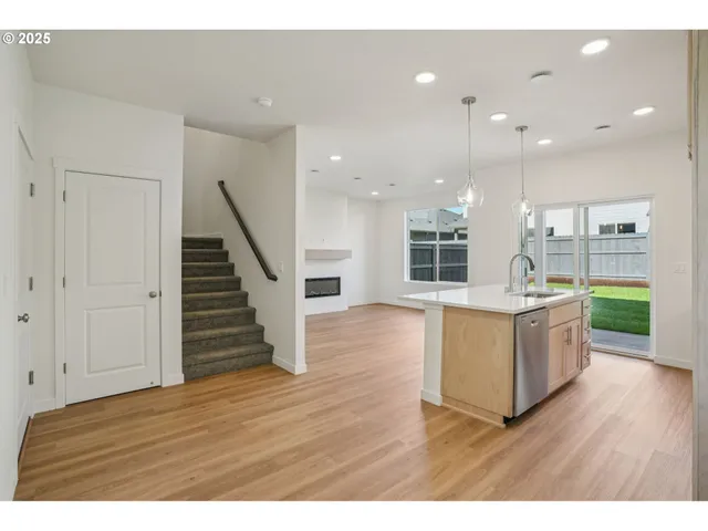 a living room with wooden floors and kitchen view