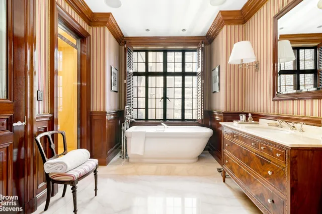 a spacious bathroom with a tub a double vanity sink a mirror and a large window