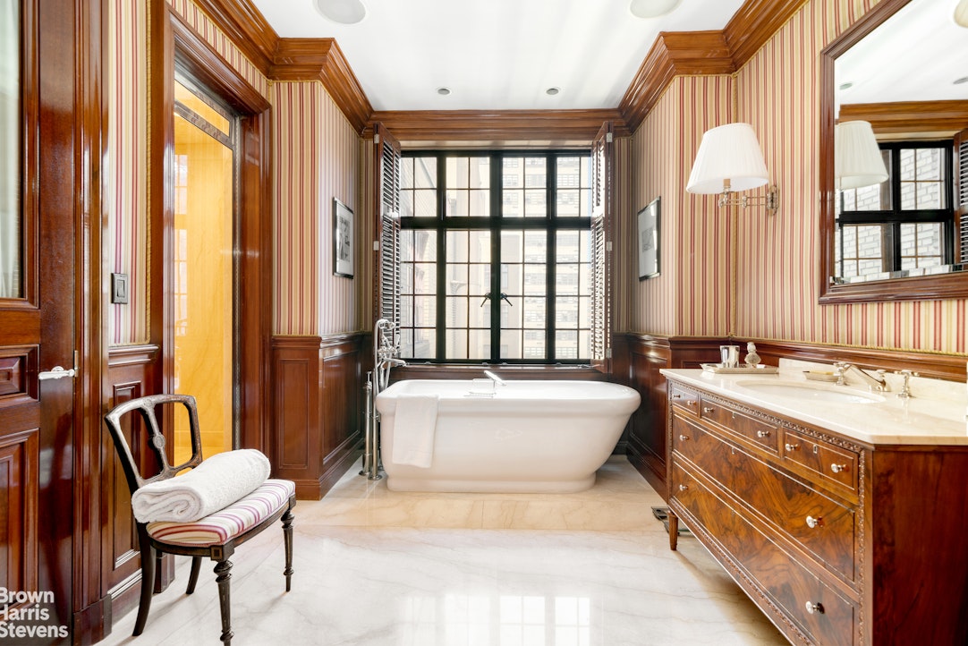 116 East 68th Street, Unit 7/8D Manhattan, NY 10065 - Photo 9 of 14 a spacious bathroom with a tub a double vanity sink a mirror and a large window