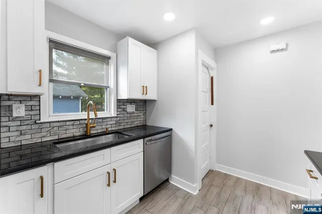 a kitchen with granite countertop white cabinets and a sink